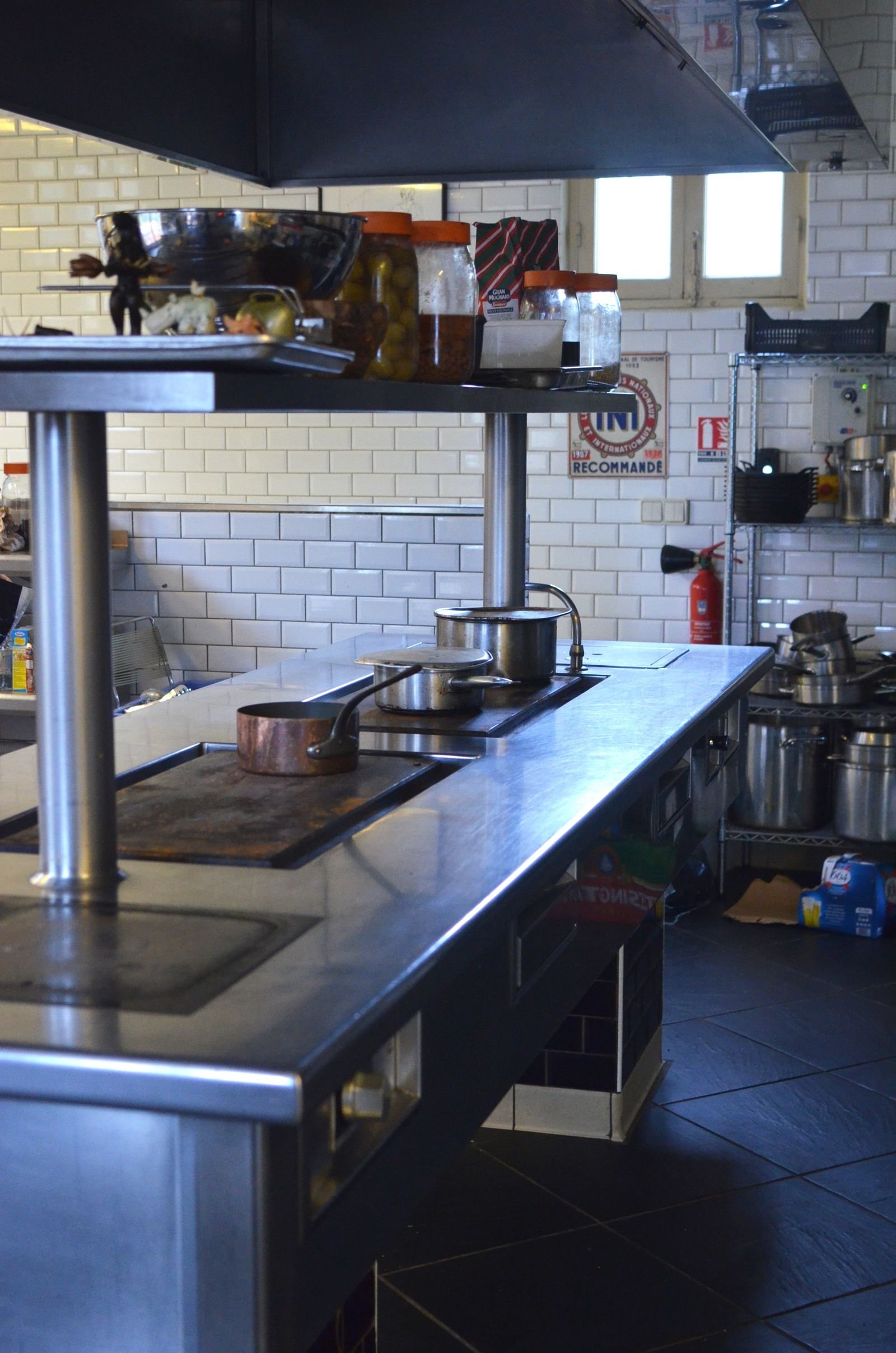 Cuisine professionnelle vide entièrement en inox, pianos et plans de travail dégagés avant dégraissage de la hotte et des points aveugles
