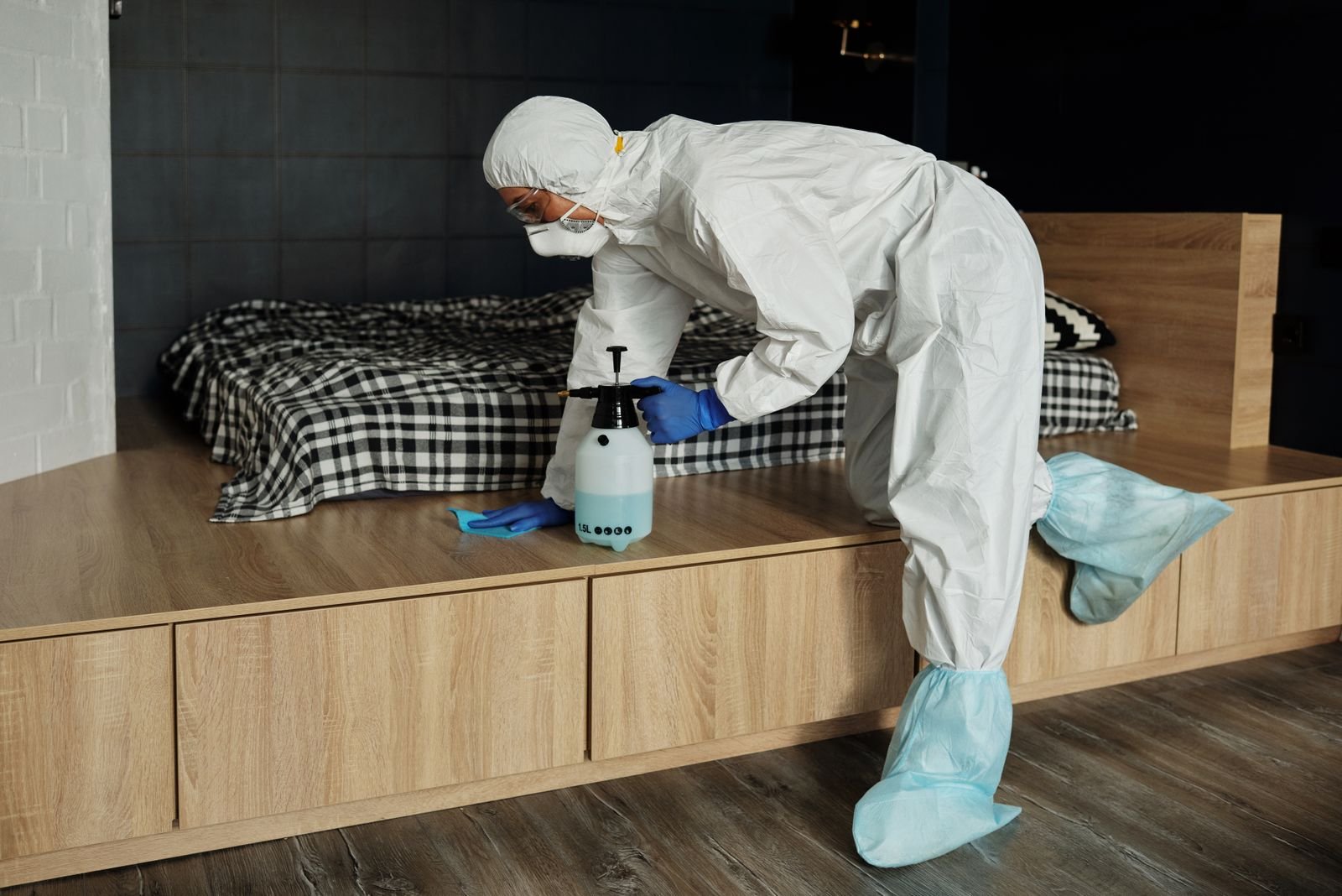 Opérateur en combinaison intégrale et protection respiratoire désinfectant une chambre, protocole appliqué lors d'une intervention après décès