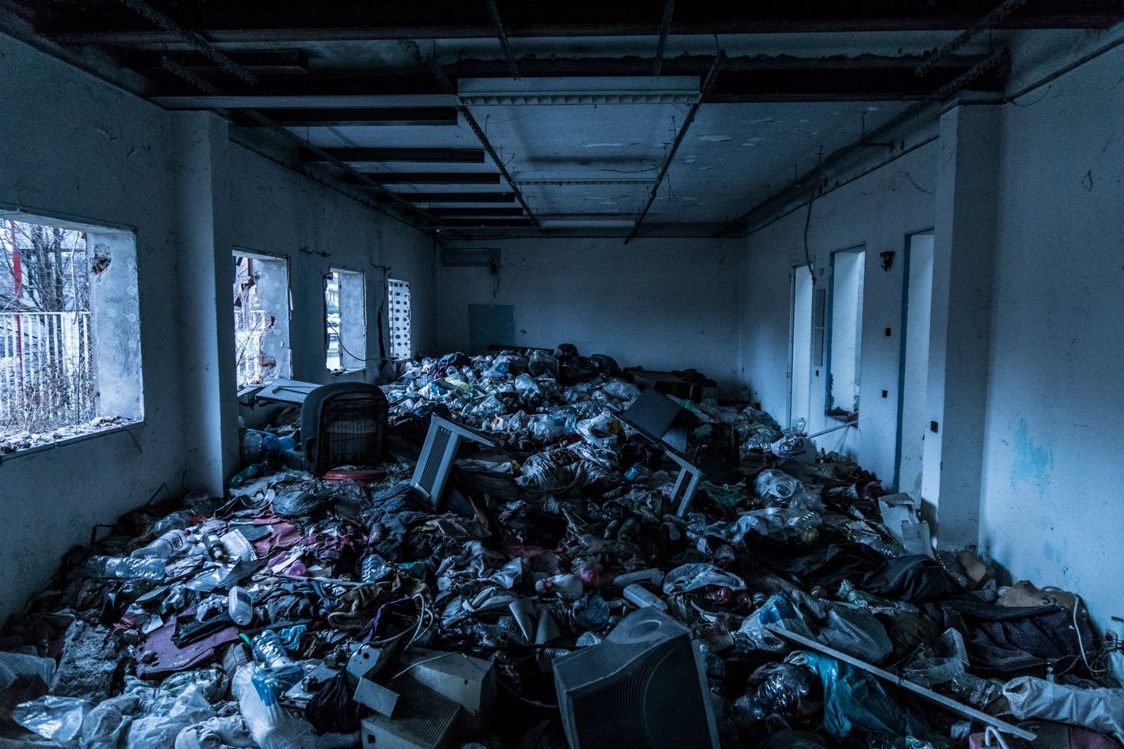 Intérieur de local laissé à l'abandon, encombré de déchets et de gravats, état rencontré dans les rez-de-chaussée fermés de longue date
